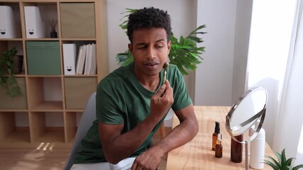 Young african american man using a jade roller for facial massage