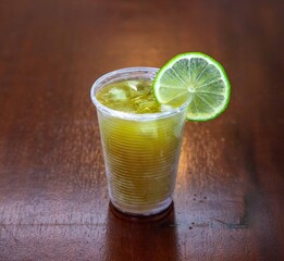 Traditional sugarcane juice, with ice and lemon, in a disposable plastic cup.Caldo de cana, garapa de cana