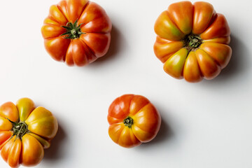 Top view of a composition of Sicilian ribbed tomatoes on a clean white background, creating a fresh and appetizing food scene ideal for culinary, organic, and Mediterranean themes.