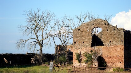 Ancient architectural remains stand against a clear sky, showcasing historical stone and brickwork...