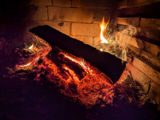 Beautiful wood log burning in a stove with flame around. Low key image. Shallow depth of field.