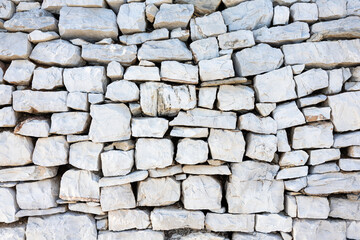 Rugged Gray Stone Wall Of Stacked Rocks With Sparse Dry Grass Detailing