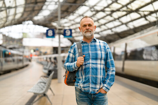 Man standing confidently at a train station platform in daytime