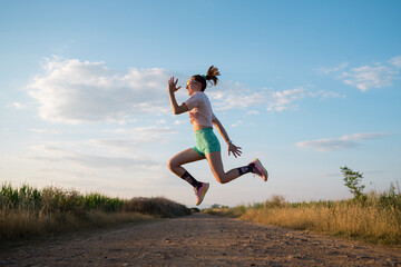 Woman runner jumping enjoying freedom on dirt road
