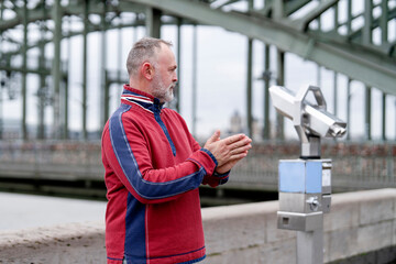 Man using a telescope near a bridge in the city