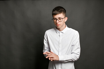 young man standing rubs his hands in front of him with his hands. it symbolizes a successful business, justified expectations. young guy with glasses on gray background rubbing his hands.