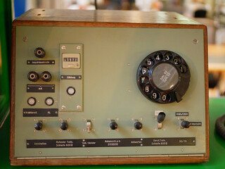 A vintage electronic control unit featuring a rotary dial, switches, connectors, and analog components. The device reflects classic engineering and retro industrial design. Ideal for illustrating