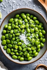 there is a bowl of green beans with salt and limes on the side