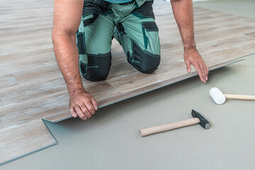 Floating floor work. The worker inserts the board of vinyl plank to the click system of Floating floor.