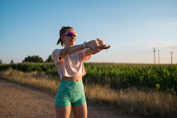 Woman stretching arms before outdoor run at sunset