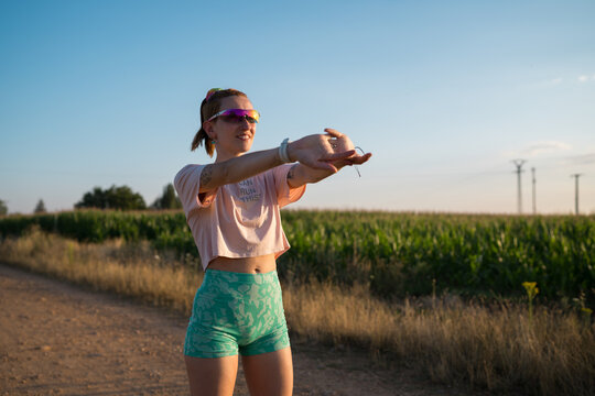 Woman stretching arms before outdoor run at sunset