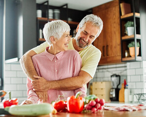 Portrait of happy senior mid aged mature couple prepering meal with fresh vegatebles in kitchen at...
