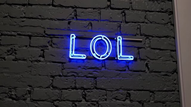 Blue neon lol text glowing on dark brick wall, modern slang abbreviation for laughter and humor concept in social media communication