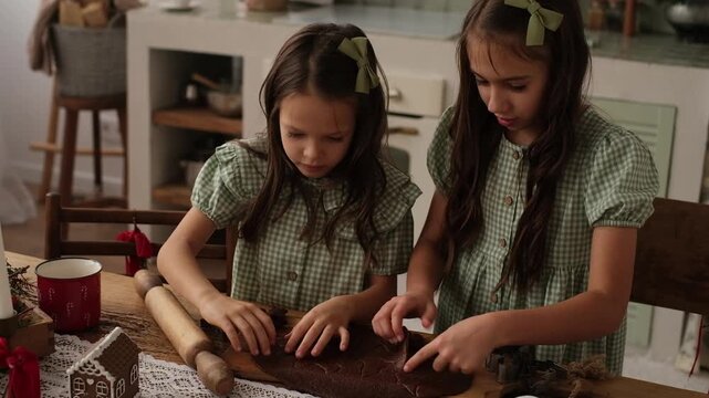 Girls make New Year's gingerbread cookies out of dough. Preparations for Christmas