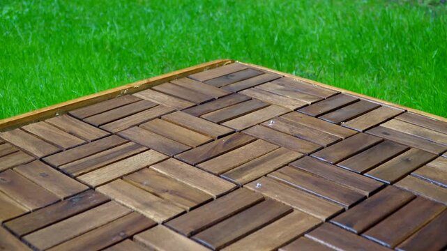 Composition of wooden parquet and grass in an outdoor setting during rainy weather. Focus and depth of field are selective. A romantic rainy landscape in the garden.