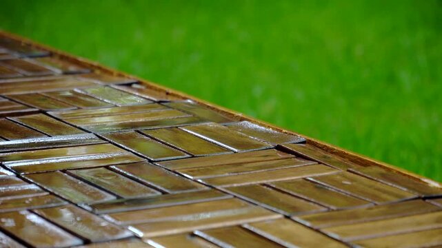 Composition of wooden parquet and grass in an outdoor setting during rainy weather. Focus and depth of field are selective. A romantic rainy landscape in the garden.