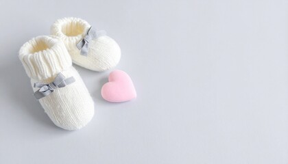 Tender White Knitted Baby Booties, Pink Heart, and Soft Background for Newborn Announcement.