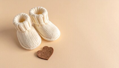 Adorable Hand-Knitted White Baby Booties, Newborn Shoes, and Felt Heart on Beige Background with Copy Space