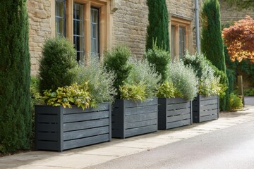 Planters filled with lush greenery line a charming stone house along a quiet street in the afternoon light, creating a serene and inviting atmosphere for visitors