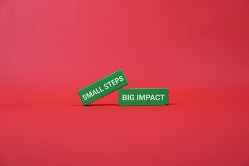 Two green blocks with 'Small Steps' and 'Big Impact' rest on an red backdrop, illustrating how...