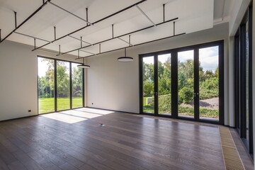 Obraz premium Spacious living room with sleek design and large windows allowing natural light to fill the area. Green landscape visible outside creates a calm atmosphere