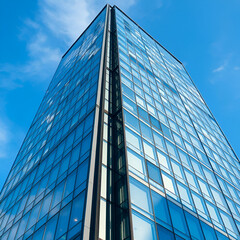 Obraz premium Ultra-realistic modern high-rise building, glass and steel facade, clean architectural lines, sunny blue sky, soft shadows, detailed reflections on windows, photographed with a high-resolution DSLR, w