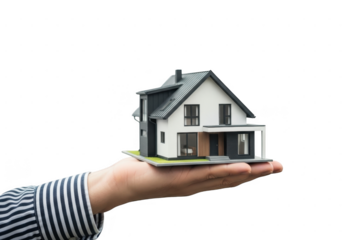 Small model of a modern twostory house resting on an open human hand, isolated on transparent background