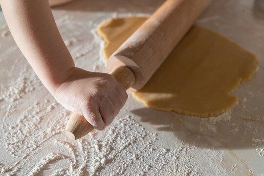 A family baking scene with children preparing German-style cut-out cookies. Little hands working with flour, dough, and festive cookie cutters.
