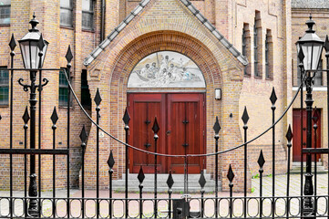 black entrance gate with behind it a Dutch church with brown wooden entrance doors