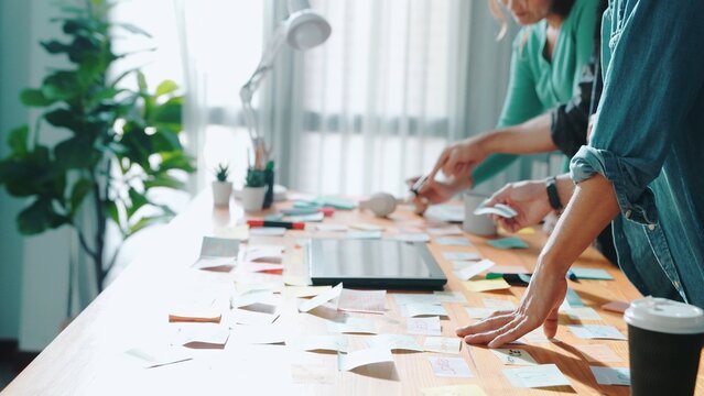 Skilled business team looking at laptop and pointing logo design while making decision to choosing main theme color and planning marketing campaign. Smart start up group working together. Symposium.