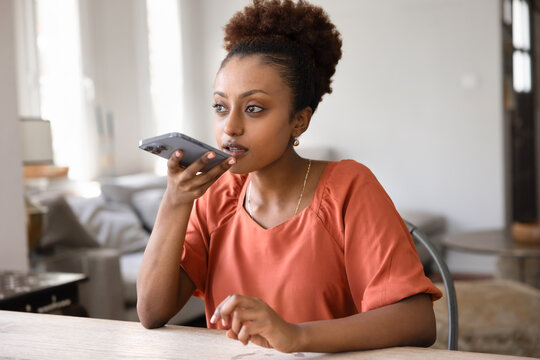 Thoughtful serious young African American woman sending voice message