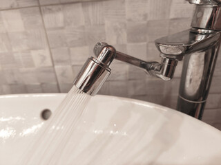 Close-up Faucet with water-saving rotating Spray Nozzle. Aerator. Water flows Eco-friendly and environmentally friendly. Modern bathroom Tap near sink. Adapter to reduce water loss. Horizontal photo.