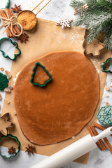 Rolled out pastry dough with cut out Christmas tree shapes on white marble table. Preparation of homemade gingerbread cookies, top view