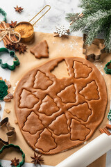 Rolled out pastry dough with cut out Christmas tree shapes on white marble table. Preparation of homemade gingerbread cookies