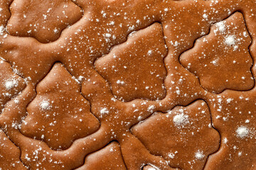 Christmas cookies festive background. Rolled out pastry dough with cut out Christmas tree shapes close up, texture. Preparation of homemade gingerbread cookies, top view