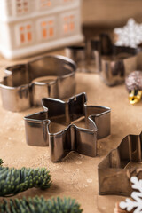 Snowflake cutter for baking Christmas gingerbread cookies on brown table. Festive holiday atmosphere with pine branches and Christmas decor