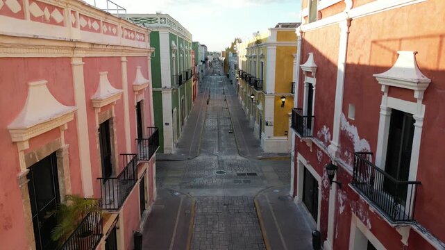 flying above scenic colorful colonial street in campeche yucatan peninsula (spanish architecture streetscape scene) gulf mexico sunrise glow cornice building beautiful downtown city center aerial view
