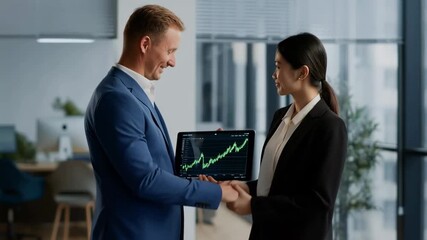 Business agreement handshake with tablet showing rising stock chart in modern office - Powered by Adobe