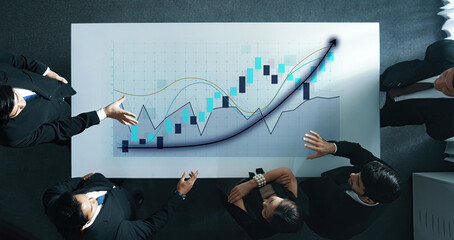 A business team is engaged in a strategy session, analyzing financial charts and graphs on a sleek table, emphasizing teamwork and growth in a modern office environment. Axiom