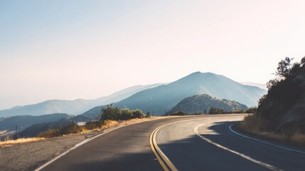 winding mountain road under clear sky, soft light, atmospheric haze, minimalistic travel vibe, serene and open landscape, peaceful and inspiring