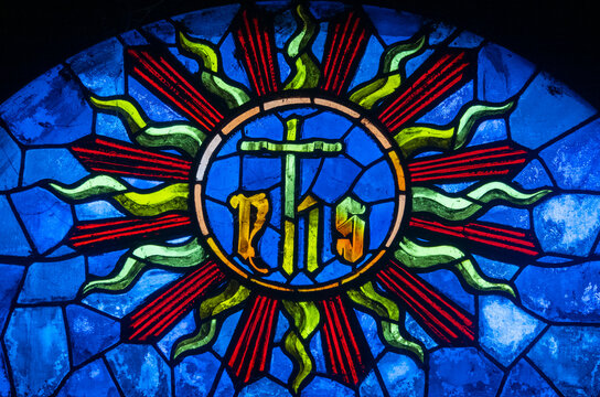 Antique stained glass window depicting the IHS Christogram. - Powered by Adobe