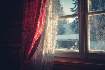 Snowy cabin window view with frost gentle sunlight red floral curtain lace cozy wooden interior winter morning peaceful serene rustic tranquil atmosphere