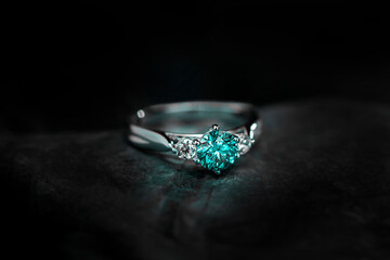 A blue diamond ring with a diamond in the center and three diamonds on the sides