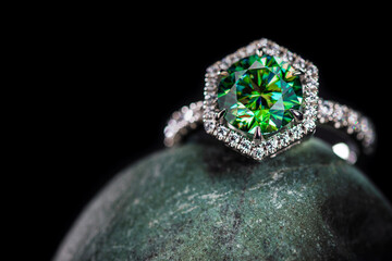 A green diamond ring sits on a rock