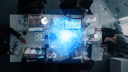 A top-down view of a business meeting showcasing professionals collaborating with digital data visualization and graphs to enhance strategic decision-making. Trope