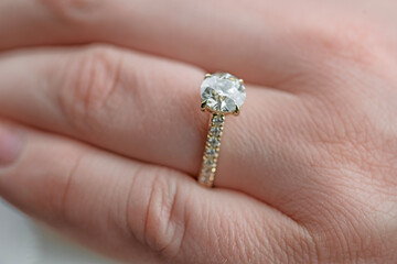 A woman is wearing a gold ring with a diamond in the center