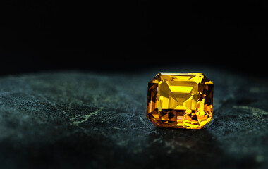 A yellow gemstone sits on a dark surface