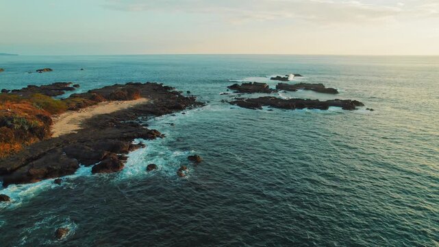 Rocky coastline with waves crashing on rugged shore during sunset Costa Rica