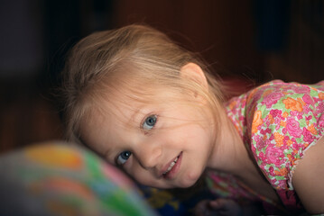 A young girl is laying on a bed with her head on a pillow
