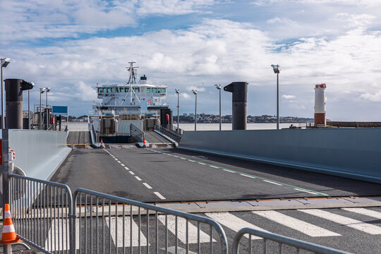 the Royan ferry terminal ramp extending towards a large white ferry waiting to load or unload. The scene is dominated by concrete barriers and a metal guardrail in the foreground, with a small
